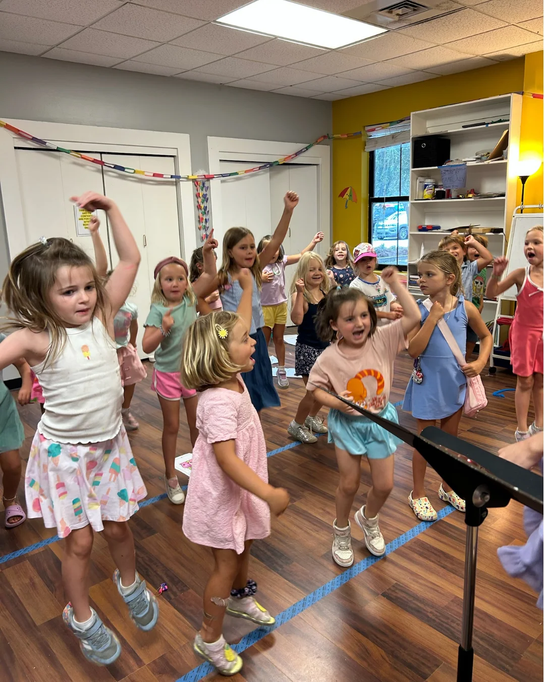 A smiling young girl holding soft pink poms during preschool music lessons at FAME Performing Arts in Mount Pleasant.