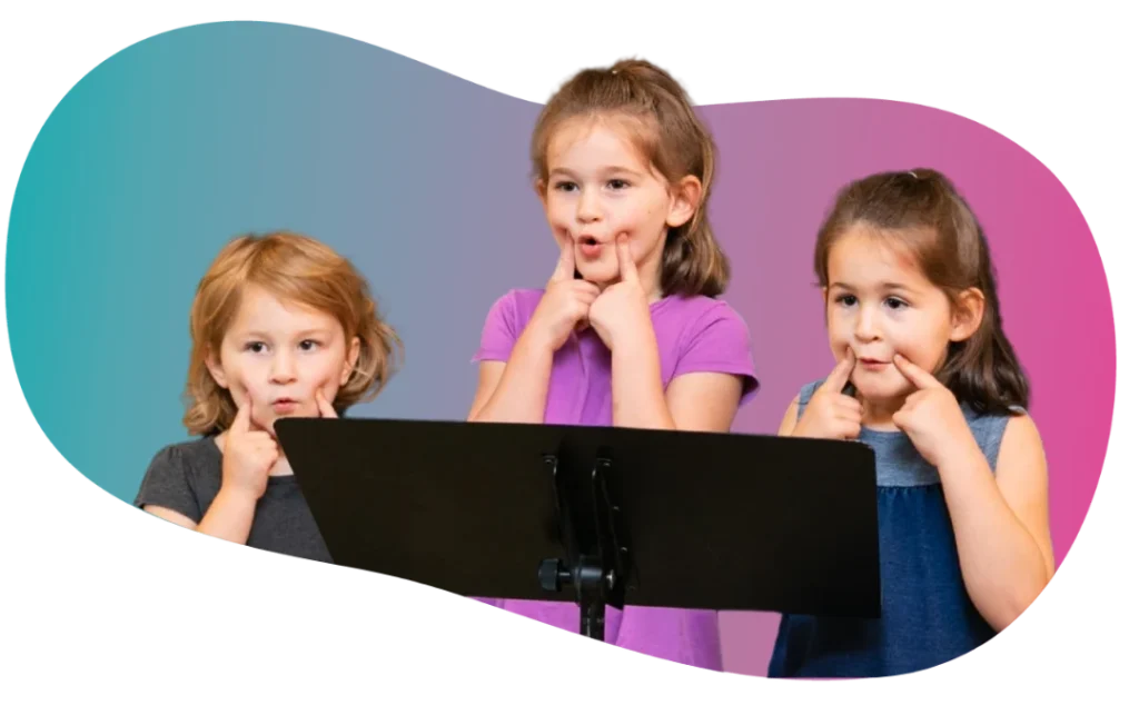 Three young children standing at a music stand practicing vocal warm-up exercises with facial expressions during a group voice class at FAME Performing Arts.